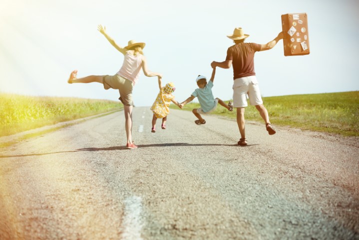 Happy family holding each other hands on sunny country road
